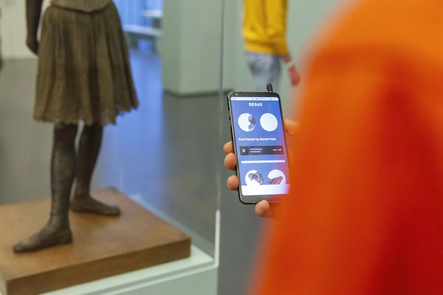 Een bezoeker van de Kunsthal luistert een audio opname op zijn telefoon waarin Remses Rafela zijn blik op het veertienjarige danseresje deelt.