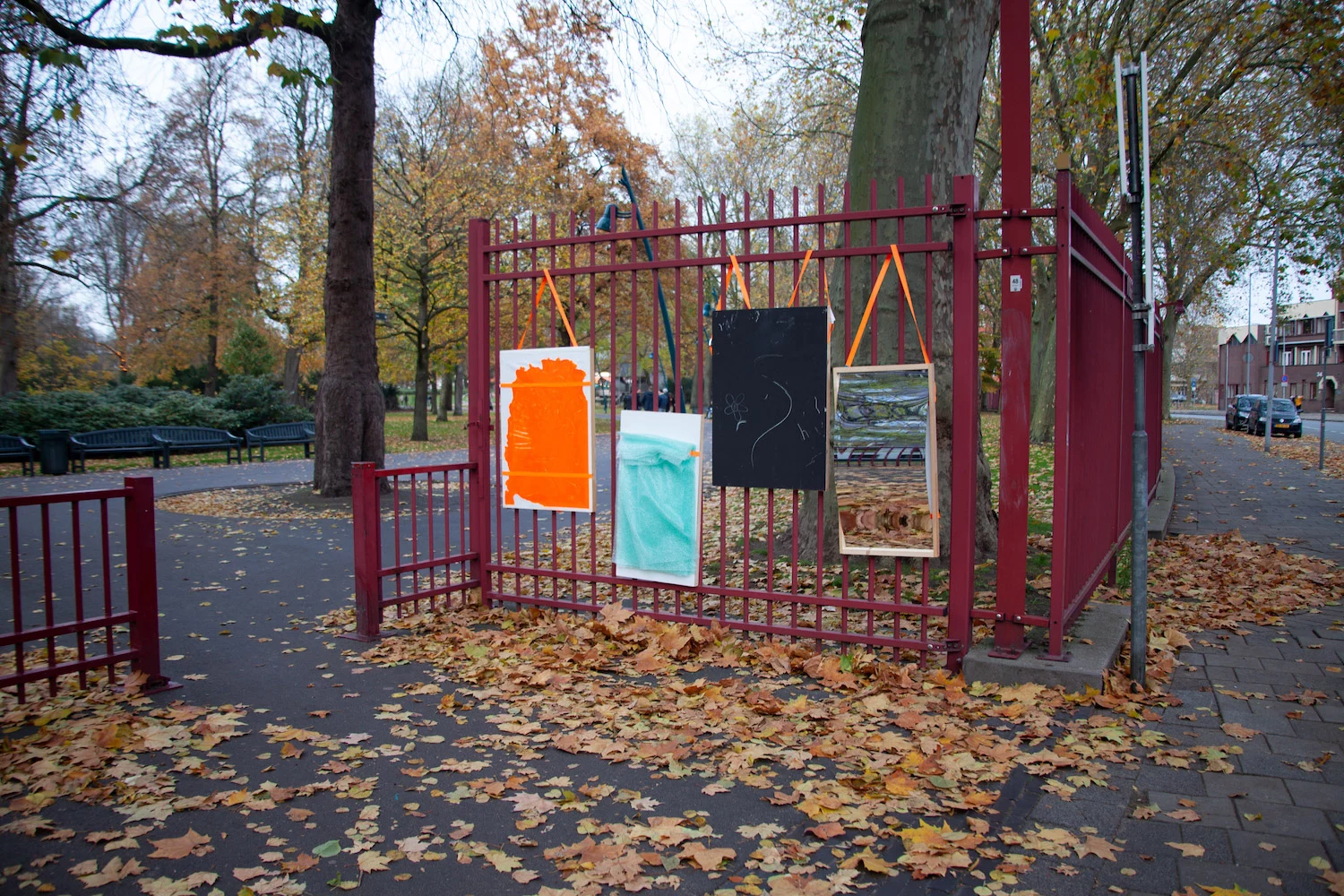 Aan een hek bij een park hangen vier borden, een vervormende spiegel, een krijtbord en twee met een textuur. De borden zijn ingezet als experiment om te kijken of jongeren op deze manier afgeleid worden van hun telefoonscherm.